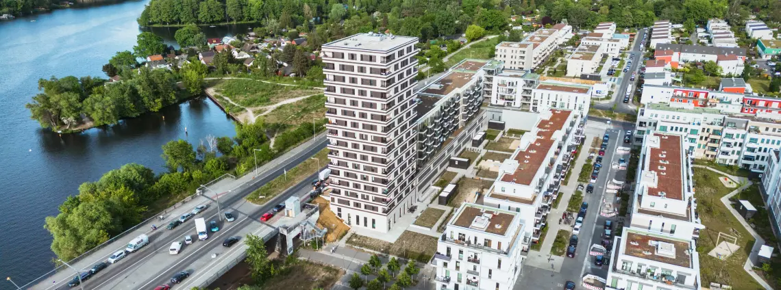 Eine moderne, begrünte Wohnsiedlung am Fluß mit einer Autobrücke am Rand