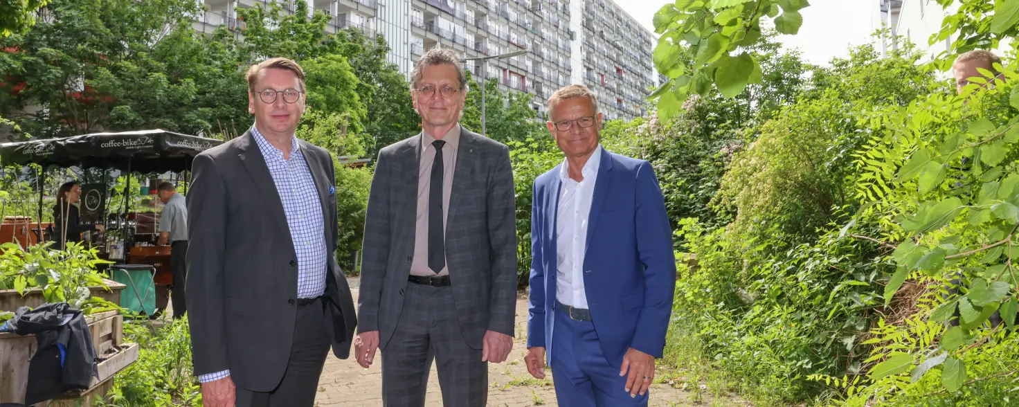 Drei Geschäftsführer in Anzügen stehen vor dem Gebäudekomplex Pallasseum in Berlin-Schöneberg.