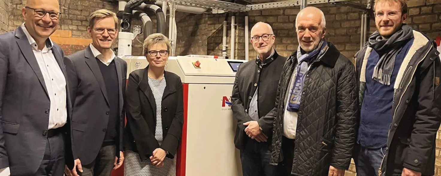 Personen die vor einem Blockheizkraftwerk mit Gaskessel stehen